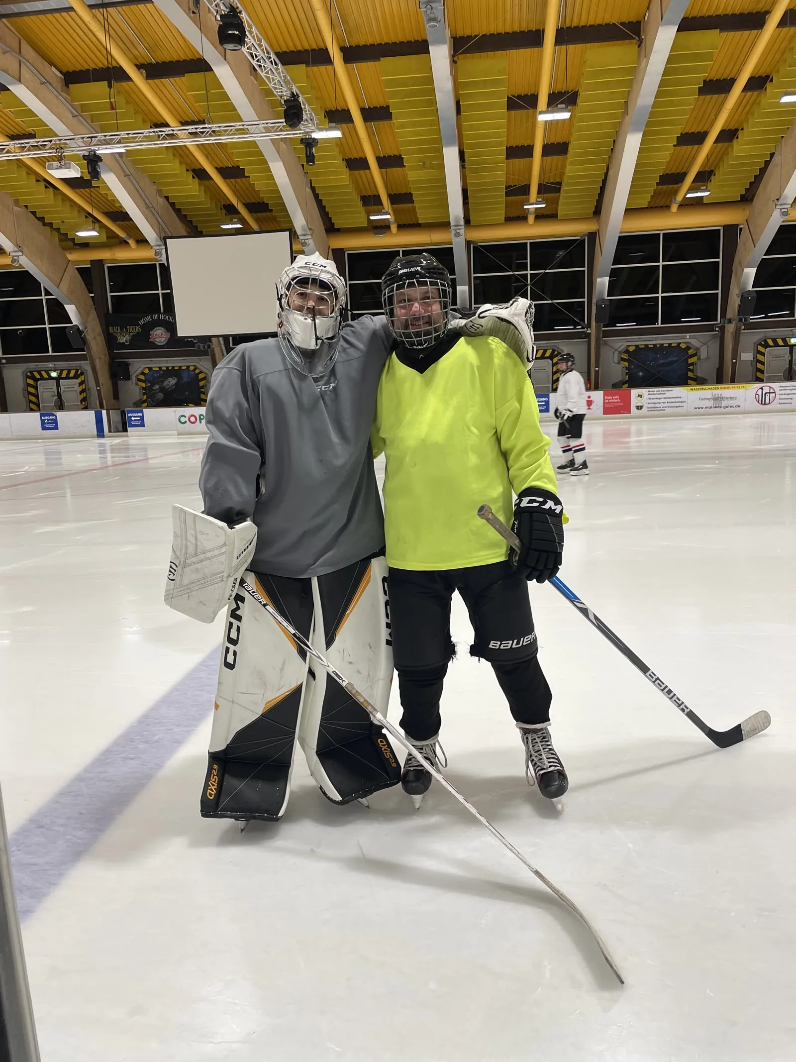 Two hockey teammates on the ice, arms around each other